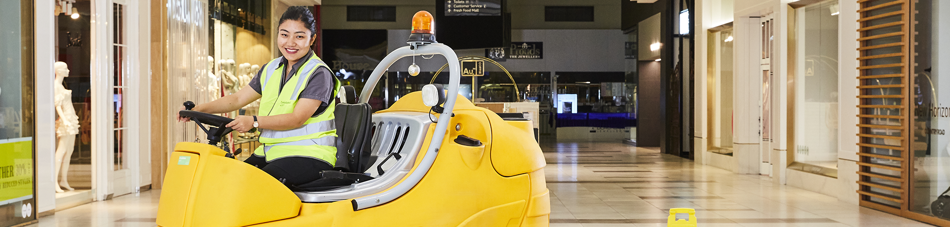 Employee driving a floor cleaning machine in a retail setting